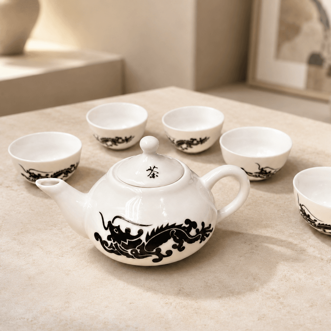 Chinese dragon teapot and small matching tea cups displayed on a neutral tabletop