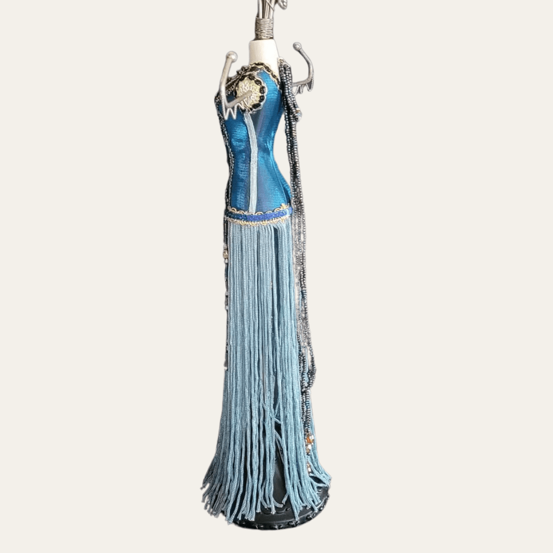 Side view of blue beaded mannequin jewellery stand with long fringe