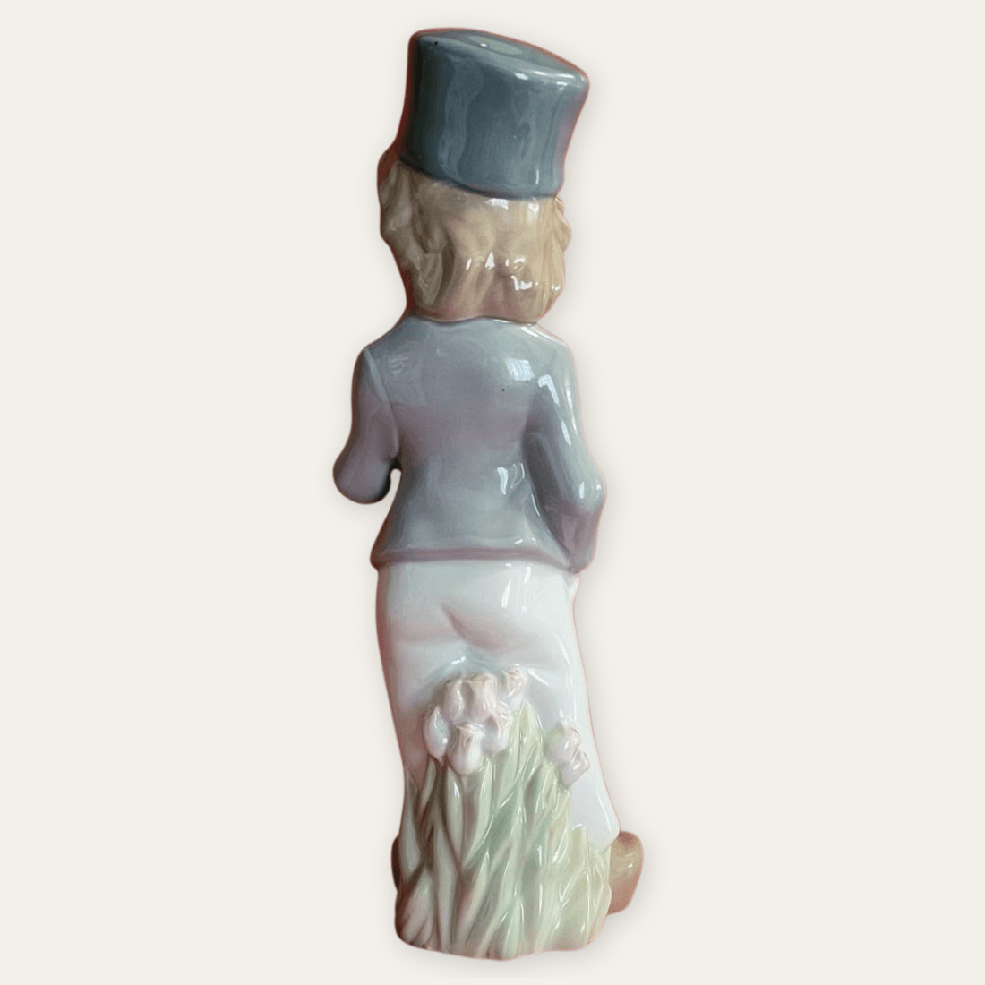 Back of the porcelain boy figurine showing the grey jacket and pink flowers around the base