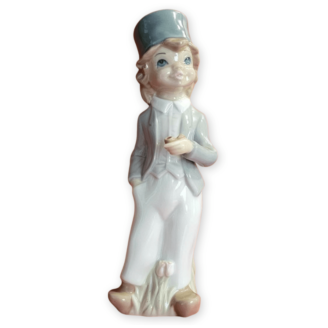 Casades boy figurine holding a pipe, with blue-grey hat and flowers at the base