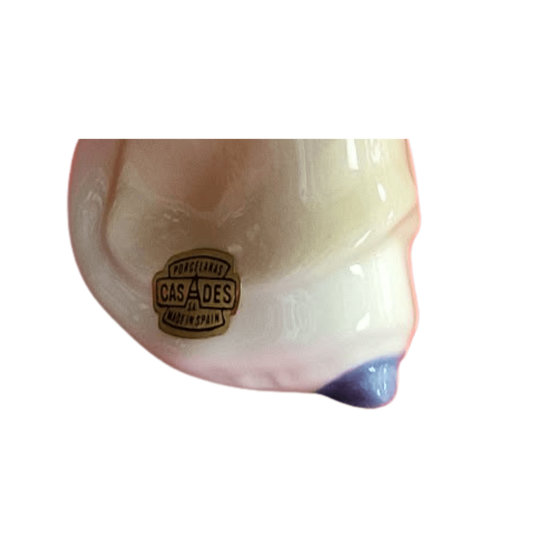 Close-up of the Porcelanas Casades Made in Spain label on the figurine's dress, beside a blue shoe
