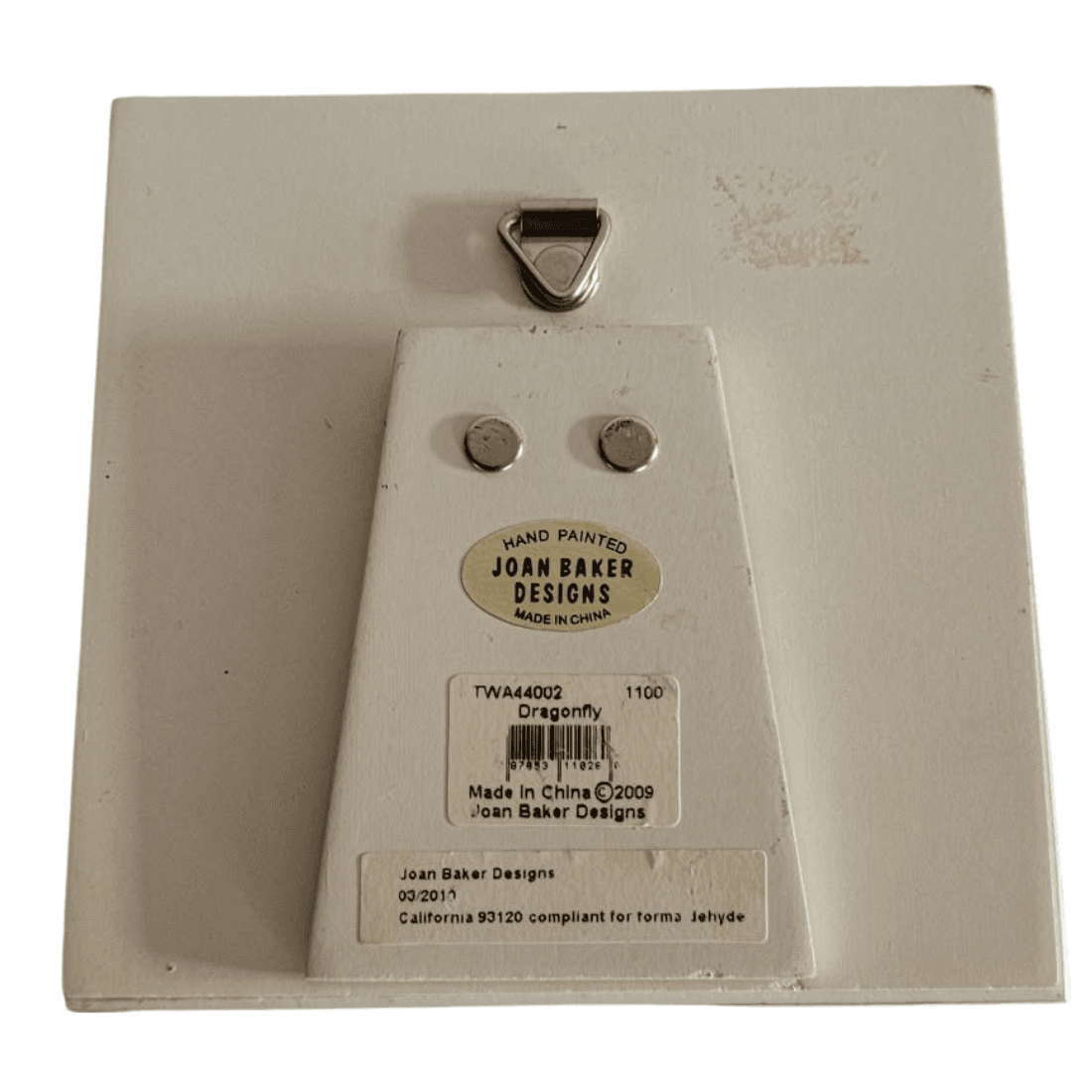 Back of Joan Baker Designs plaque showing TWA44002 Dragonfly labels, folded stand and hanging fitting