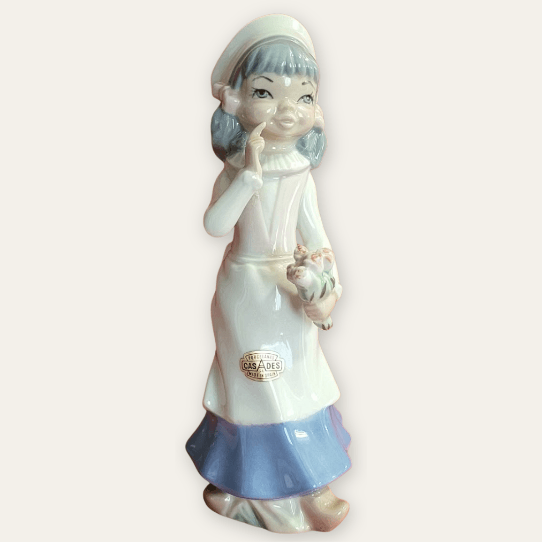 Angled view of vintage Casades porcelain girl figurine with flower basket