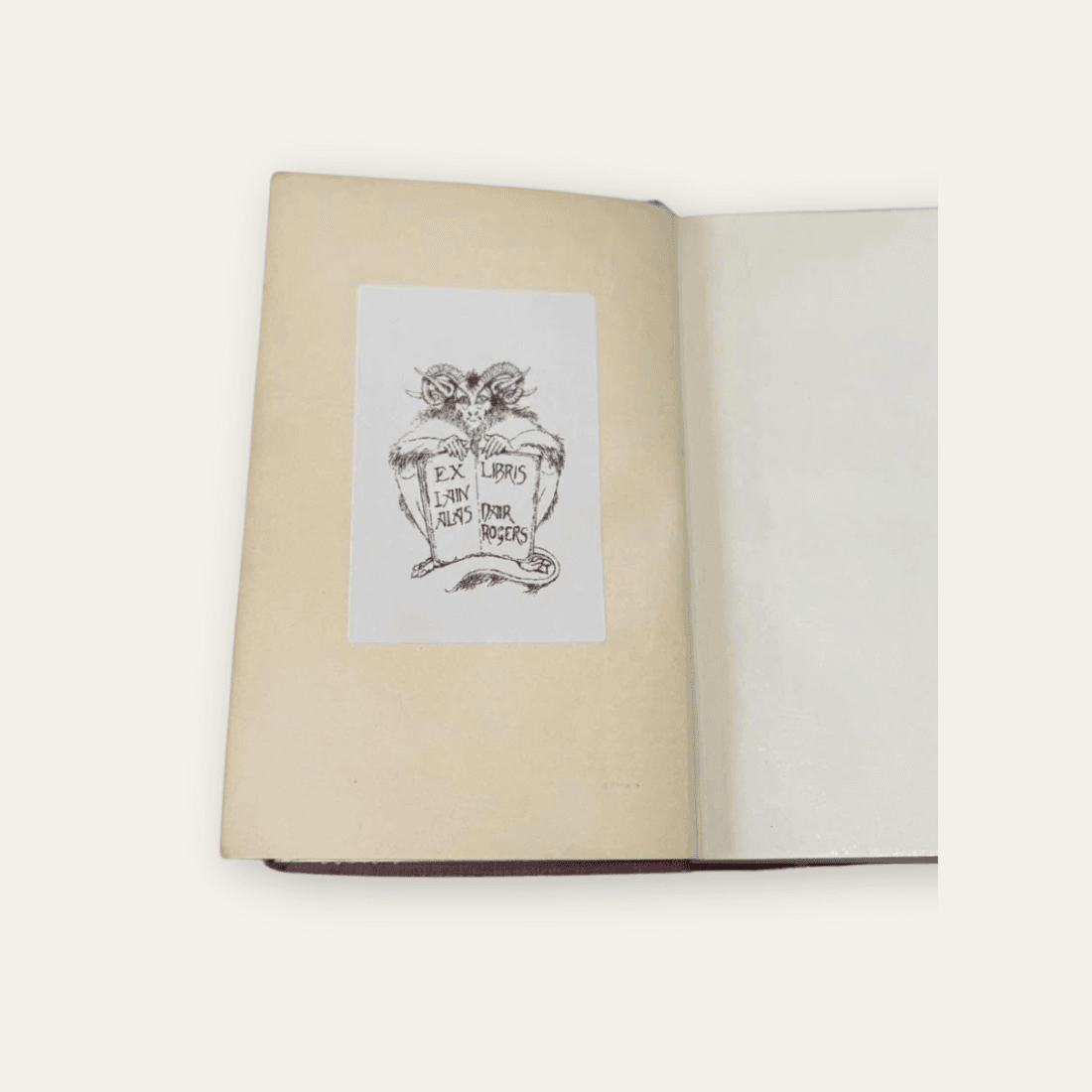 Pasted-in ex libris bookplate with an illustrated horned creature holding an open book